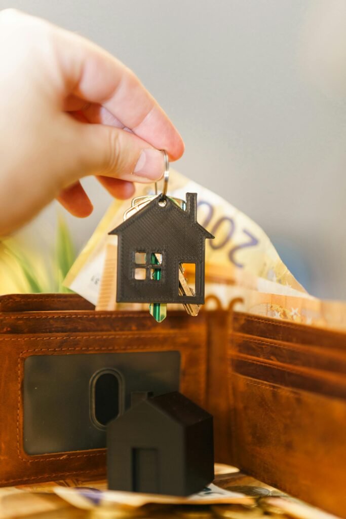 pexels-photo-30349323-30349323 A hand holds a house-shaped keychain above an open wallet with Euro banknotes.